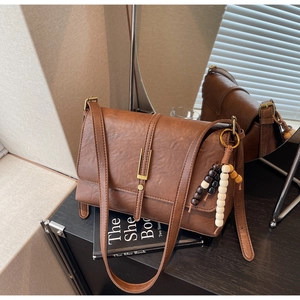 Close-up of vintage brown leather crossbody bag with decorative beads and metal buckle