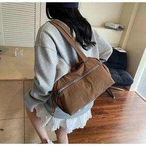 Detail view of large brown shoulder tote bag in nylon showing texture and wide strap