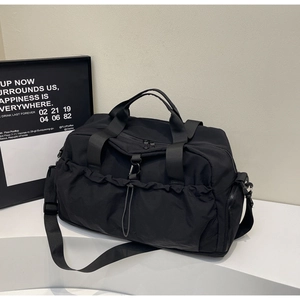 Detailed macro view of black nylon travel bag featuring drawstring pocket and metal hook
