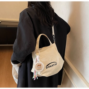 Detail of off-white canvas tote bag with BANATU logo and cute capybara pendant accessory