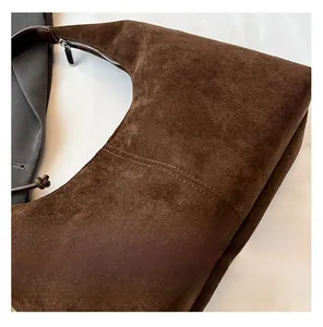 Close-up of brown suede bag showing fine texture and dark leather shoulder strap details