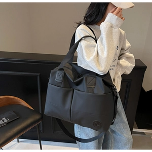 Close-up of black waterproof nylon backpack featuring dual handles and metal logo detail