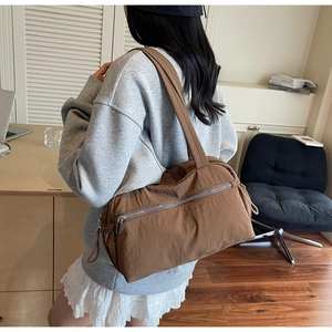Detailed side view of caramel brown tote bag showing metal zipper pocket and textured fabric