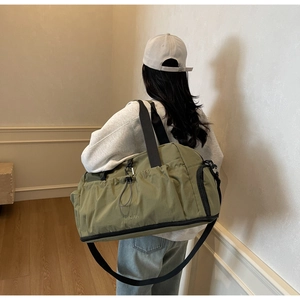 Close-up of olive green nylon fitness bag featuring Mingjia logo and durable side pocket