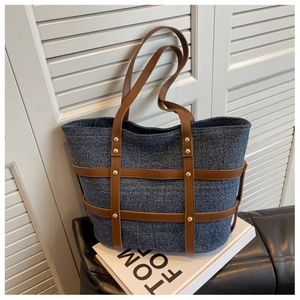 Close-up of denim texture tote bag with brown leather straps and gold rivet detailing