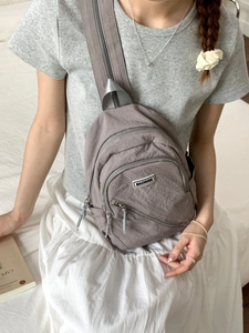 Minimalist grey nylon mini backpack for women with adjustable straps and multiple zippers