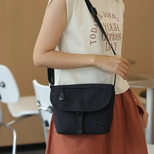 Detail einer schwarzen Umhängetasche aus Nylon, von einem Model lässig getragen