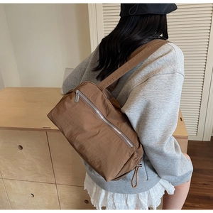 Close-up of brown nylon shoulder bag with silver zipper and textured fabric finish