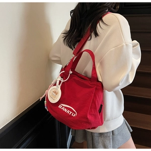 Detail of red canvas tote bag with Banatu print and decorative charm on shoulder