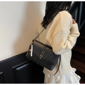 Detail of vintage black matte leather shoulder bag with a beaded tassel on stairs