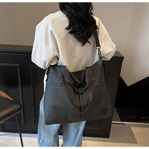 Close-up of a large black nylon tote bag showing the side profile on a female model
