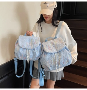 Detail of light blue quilted backpack with colorful embroidery and drawstring flap