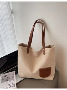 Borsa tote minimalista in tela beige con accenti in pelle marrone vicino a un laptop