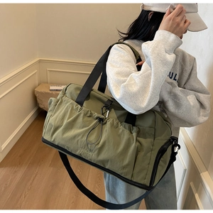 Olive green travel bag detail showing drawcord pocket, carabiner, and shoe compartment