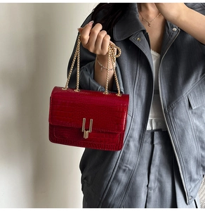 Close-up of red crocodile pattern shoulder bag with elegant gold chain and U-shaped buckle