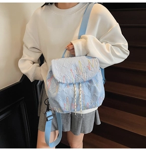 Detail showing light blue quilted backpack with colorful embroidery on wooden stairs