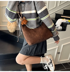 Close-up of deep brown suede hobo bag with a cute bear charm on a striped polo outfit