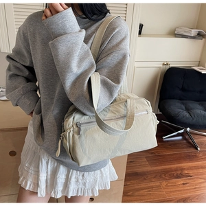 Detail of light beige tote bag featuring side drawstring pocket and front zipper