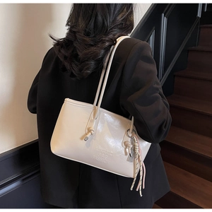 Detail of off-white leather tote bag with knotted strap and silk scarf accessory