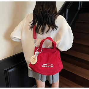Red crossbody bucket bag featuring adjustable fabric strap and cute bear charm detail