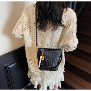 Detail of black woven bucket bag with vintage bead tassel and adjustable shoulder strap