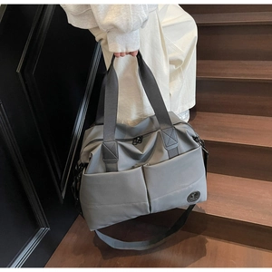 Detail of a dark grey high-capacity travel bag featuring reinforced handles and side pockets
