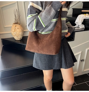 Detail view of dark brown suede half-moon crossbody bag styled on a model in a minimal setting