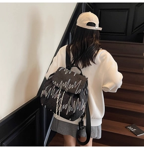 Close-up of black quilted backpack with white wave patterns and drawstring closure