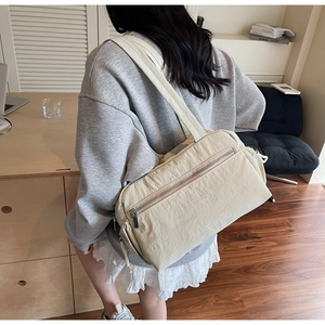 Detail of a minimalist off-white nylon tote bag with a zipper pocket in a home office setting