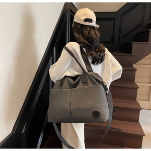 Detail of gray waterproof travel tote bag with adjustable strap and logo on stairs