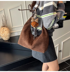 Detail of dark brown suede crescent bag with a cute plush bear charm on stairs