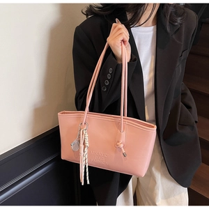 Close-up of pink leather tote bag featuring embossed logo and tennis racket tassel charm
