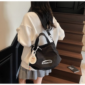 Black ruched dumpling bag with adjustable wide strap and cute charm shown on model