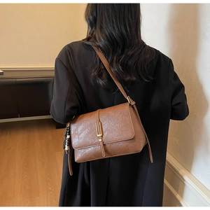 Rear view of model wearing a vintage brown faux leather crossbody bag with bead charm