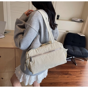 Detail view of large beige nylon tote bag with functional zippers and drawstring sides