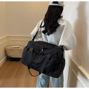 Detail showing back view of large black travel bag with adjustable strap and side pockets
