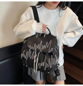 Detail view of black quilted backpack with wave embroidery and drawstring closure