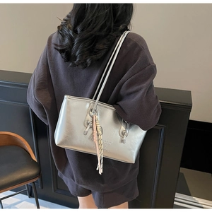 Silver metallic tote bag shown on model back view in a stylish modern interior setting