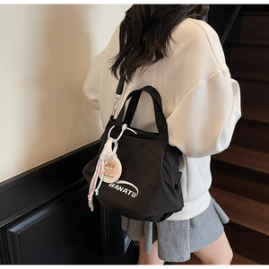 Close-up of black canvas tote bag with adjustable strap and cute cartoon capybara charm