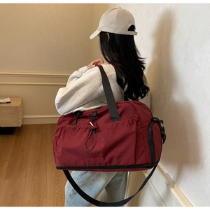 Detail of burgundy fitness bag with adjustable strap and side shoe compartment feature
