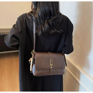 Detail of dark brown retro shoulder bag with golden buckle and colorful bead tassel