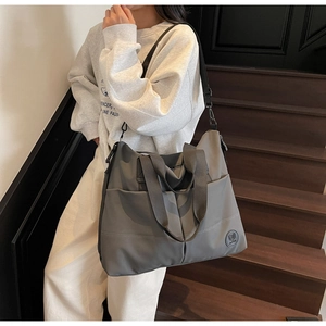 Detailed view of gray large capacity tote bag with front pockets and wide strap