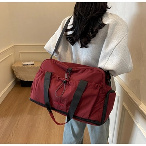 Detail of burgundy travel bag showing shoe compartment and durable nylon texture