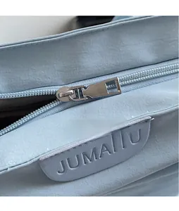 Detail of light blue fabric tote with silver polished metal zipper and brand logo patch