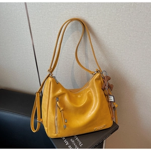 Détail du sac hobo jaune moutarde montrant le similicuir grainé et les pompons