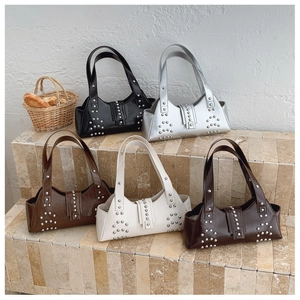 Close-up of glossy leather shoulder bags with metallic studs in multiple colors on steps
