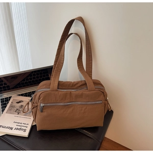 Brown casual multi-pocket tote bag with triple zipper compartments on a leather stool