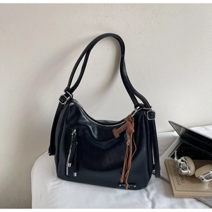 Détail d'un grand sac hobo noir en cuir avec zip argenté et breloque en corde