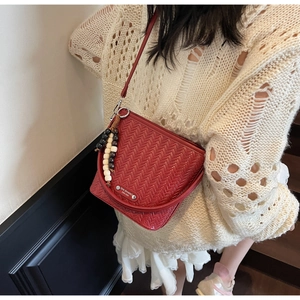 Detail of red woven texture shoulder bag with beads and silver logo plaque