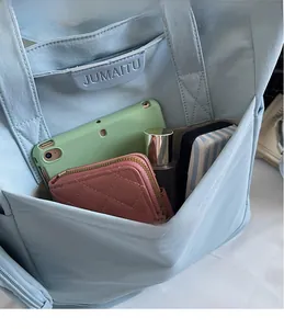 Close-up of light blue tote bag pocket holding tablet, wallet and cosmetics for daily use